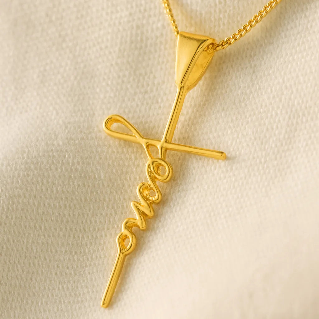 macro-do-pingente-cruz-com-escrita-jesus-sobre-tecido-claro-com-detalhe-no-brilho-do-ouro