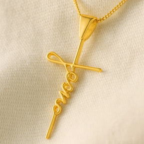macro-do-pingente-cruz-com-escrita-jesus-sobre-tecido-claro-com-detalhe-no-brilho-do-ouro